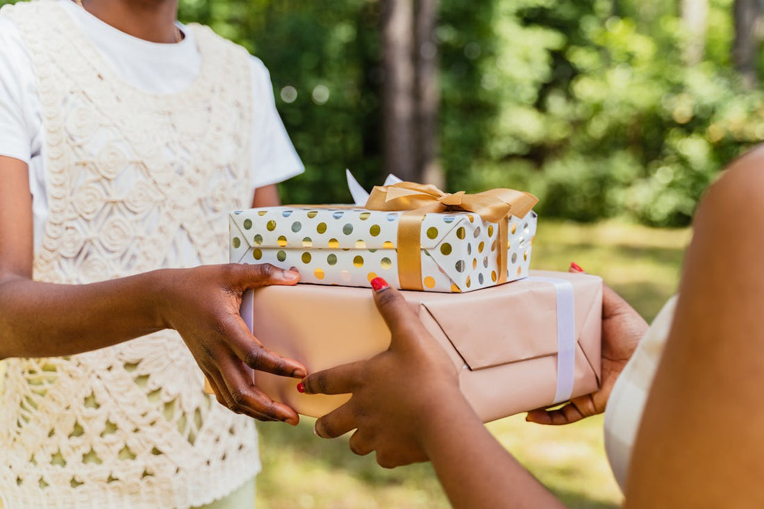 Three people exchanging beautifully wrapped gifts in an outdoor setting. wedding gift, present, outdoor celebration